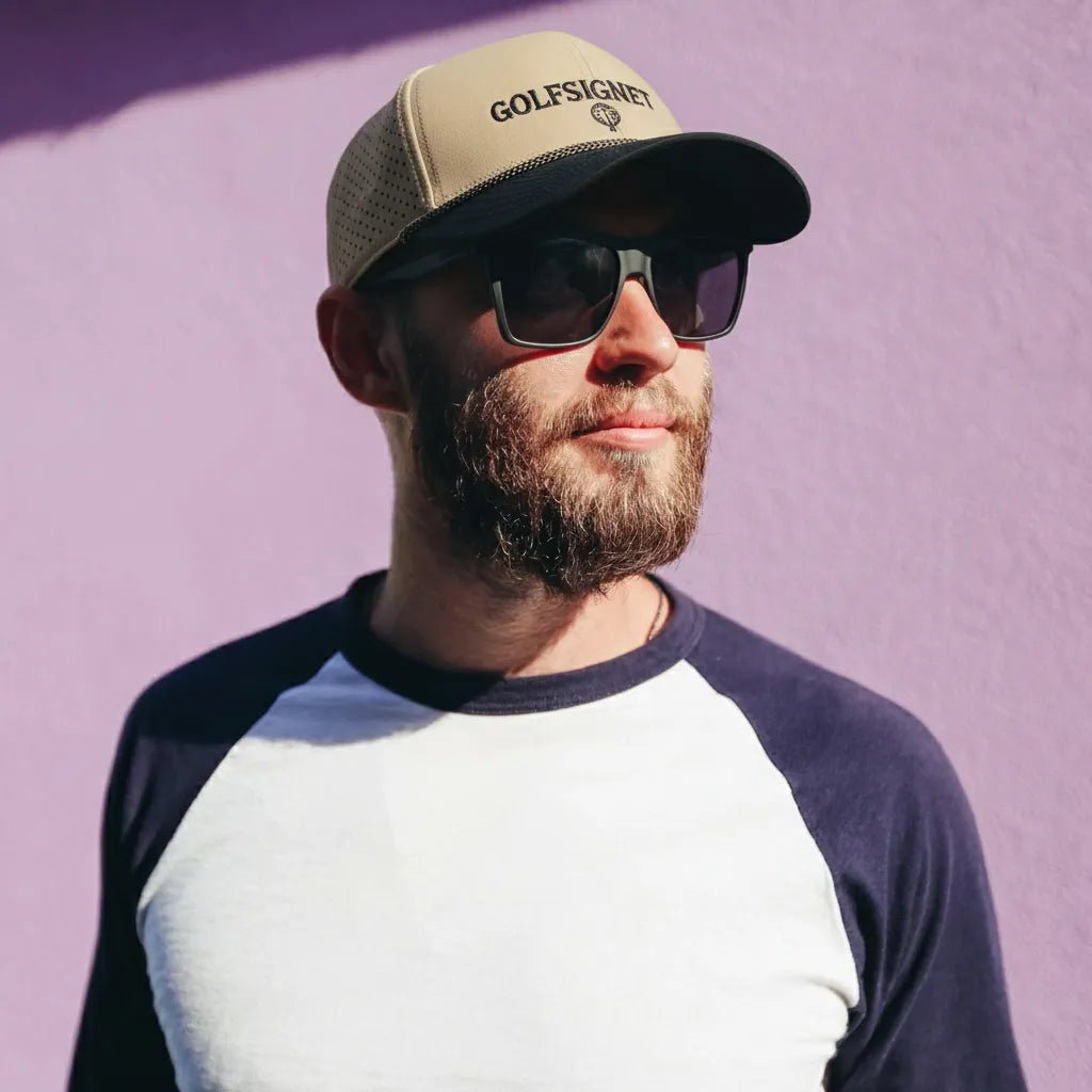 Man wearing a cap and sunglasses with a purple background