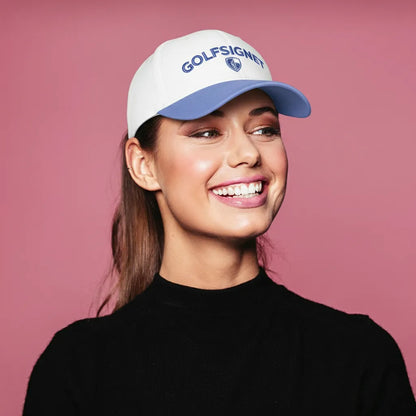 Woman wearing a white cap with 'GOLFSIGNET' logo on a pink background